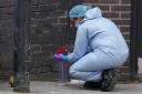A forensic investigator puts flowers into a container at the scene near the Whitgift shopping centre (Lucy North/PA)