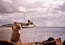 Al Goold sitting on the rocks, waving at the turbine steamer Duchess of Montrose leaving Keppel Pier