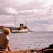 Al Goold sitting on the rocks, waving at the turbine steamer Duchess of Montrose leaving Keppel Pier